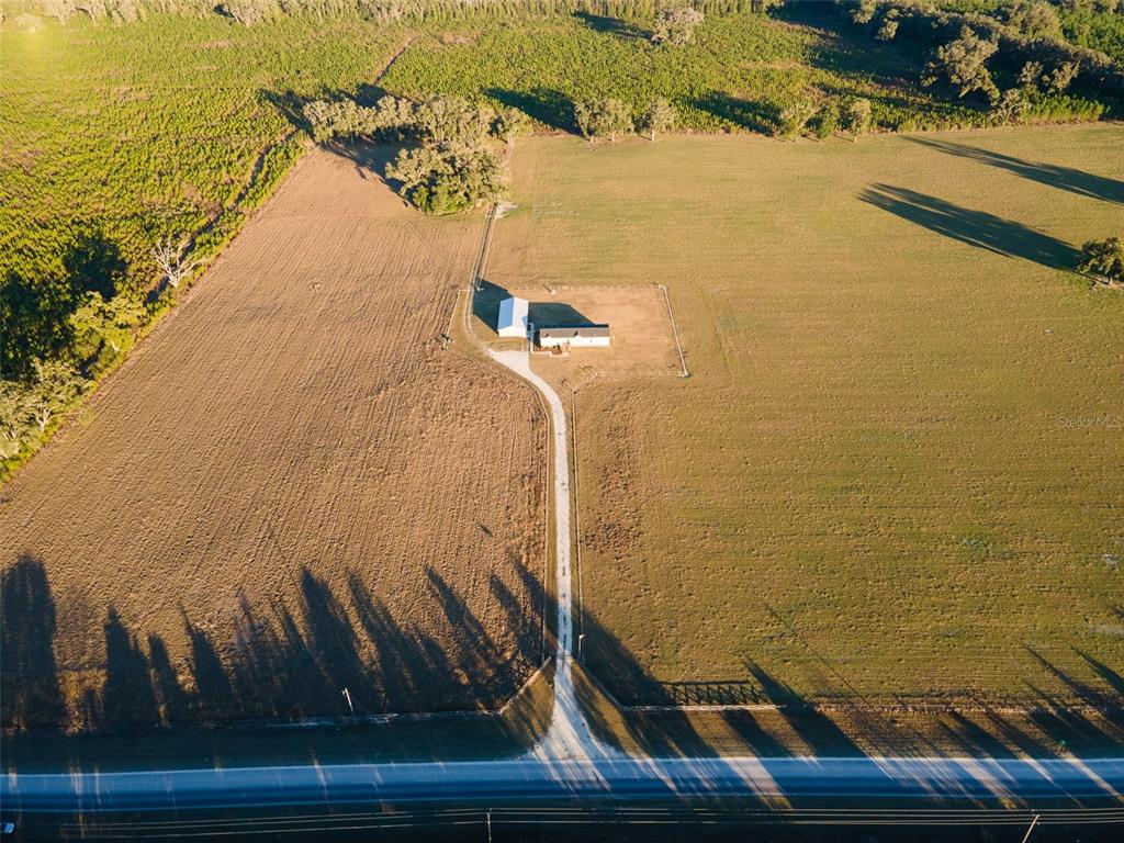 An aerial view of a house and barn situated on a large, open rural property — 001 NW 202ND STREET, NEWBERRY, FL