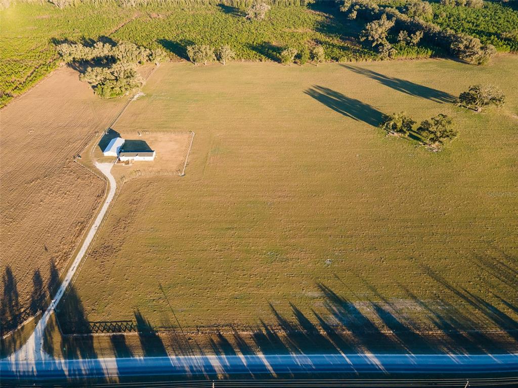 An aerial view shows a house and fenced yard situated on a large, open pasture — 001 NW 202ND STREET, NEWBERRY, FL