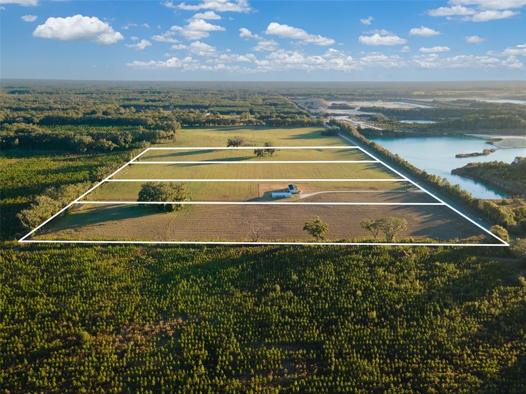 An aerial view shows a large, rectangular plot of land divided into four sections — 001 NW 202ND STREET, NEWBERRY, FL