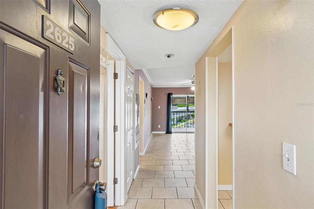 A view from an open front door into a tiled hallway leading toward a living area — 2438 ENTERPRISE ROAD UNIT 25, CLEARWATER, FL