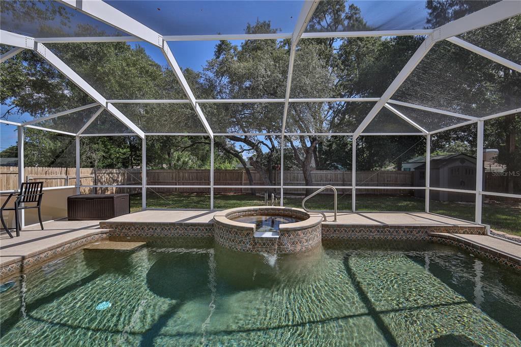 A screened-in pool area features a raised circular spa with a spillover waterfall feature — 1382 LARKIN ROAD, SPRING HILL, FL