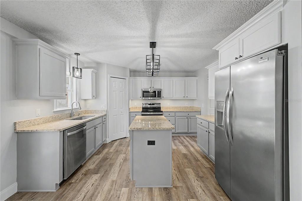 A kitchen featuring light gray cabinets, granite countertops, stainless steel appliances, and wood-look flooring — 1382 LARKIN ROAD, SPRING HILL, FL