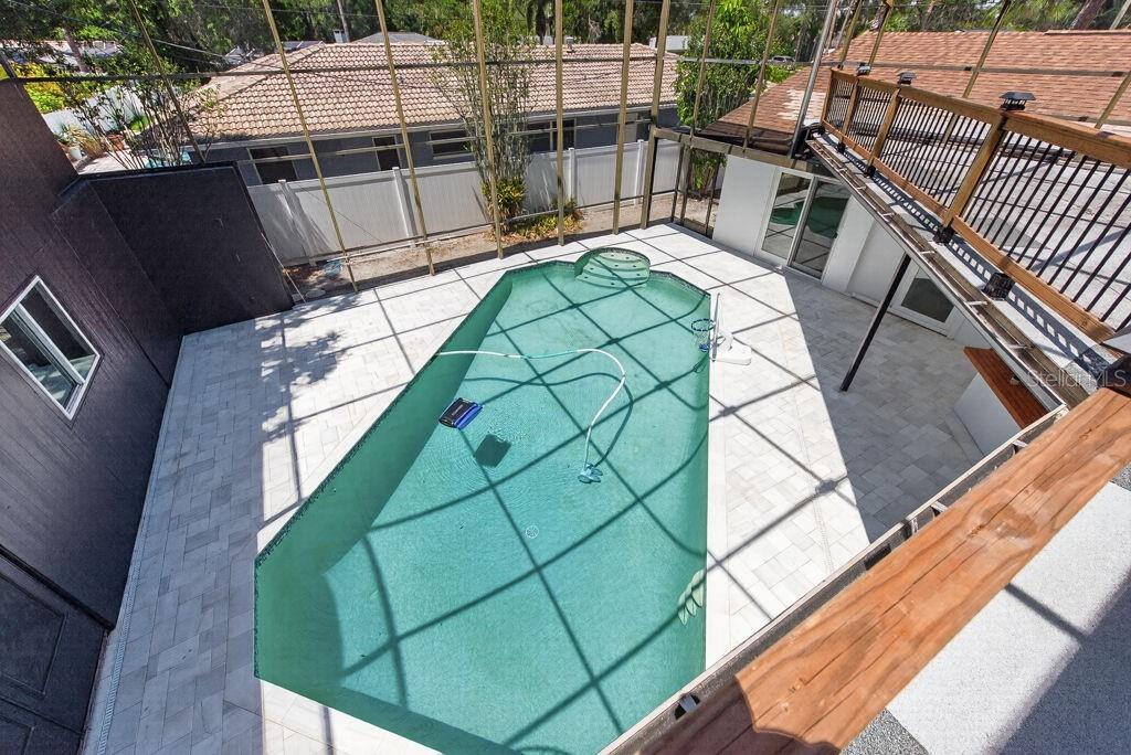 An elevated view of a screened-in swimming pool with a patio and a wooden balcony — 1461 87TH AVENUE N, ST PETERSBURG, FL