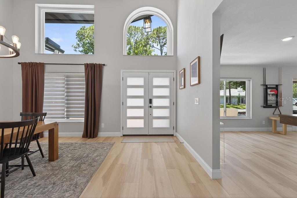 A bright entryway features light wood floors, a double front door, and high arched windows — 1461 87TH AVENUE N, ST PETERSBURG, FL