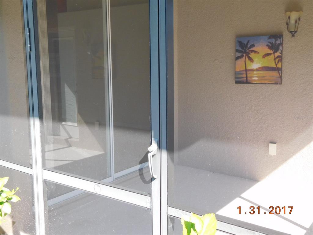 A screen door opens to a patio featuring a sunset painting on the wall — 3670 LAKEWOOD BOULEVARD, NORTH PORT, FL