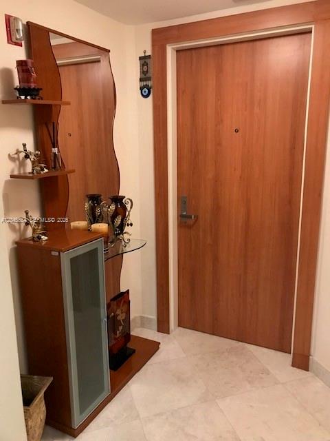 A wooden entryway cabinet with a mirror and glass door stands beside a wooden door — SURFSIDE, FL