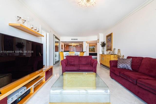 A living room features two burgundy sofas, a glass coffee table, and a wooden media console — SURFSIDE, FL
