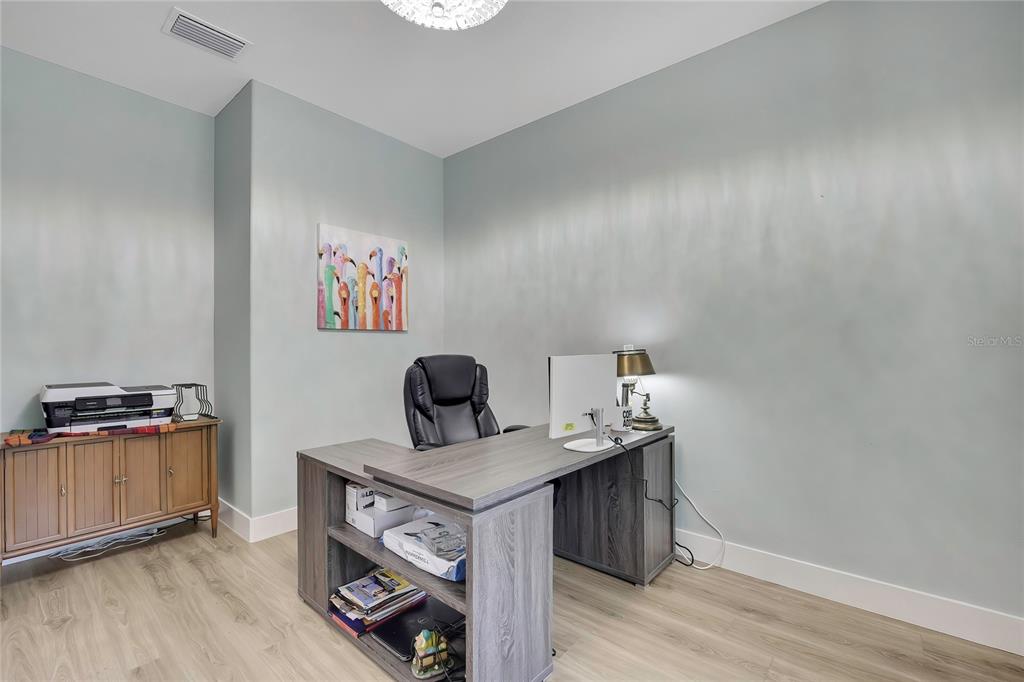 A home office features light blue walls, wood-look flooring, a gray L-shaped desk, and a printer — 3991 N BUCKHORN DRIVE, BEVERLY HILLS, FL