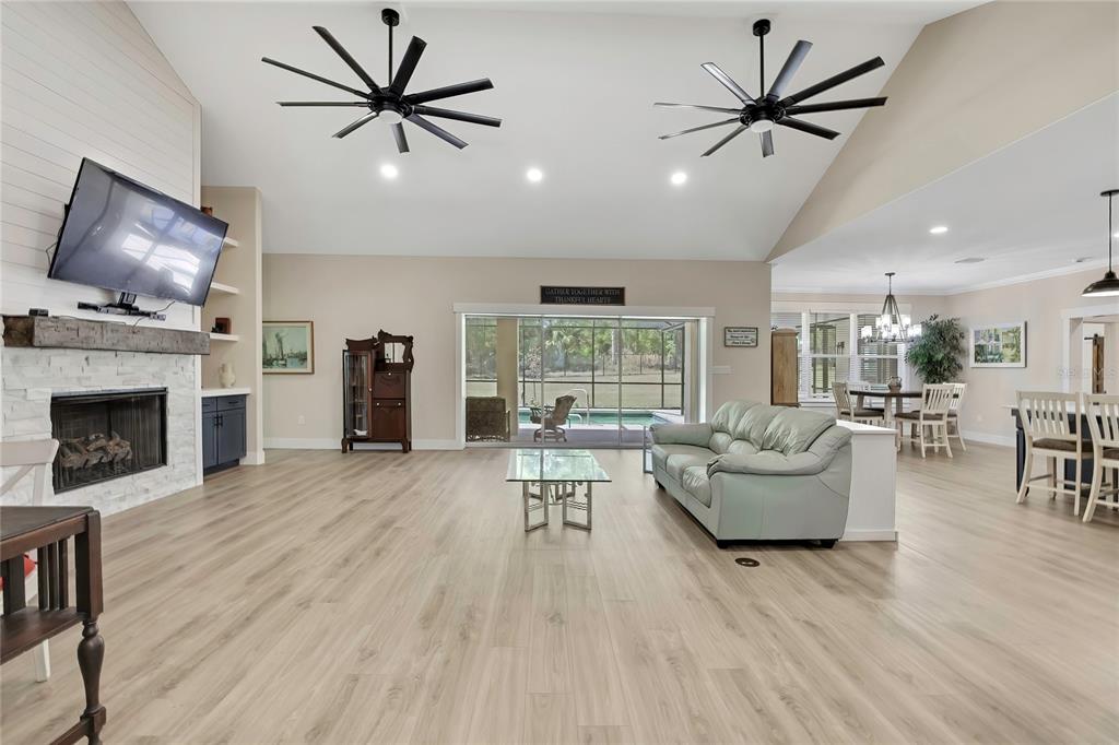 A spacious living room features light wood flooring, a stone fireplace, and two ceiling fans — 3991 N BUCKHORN DRIVE, BEVERLY HILLS, FL