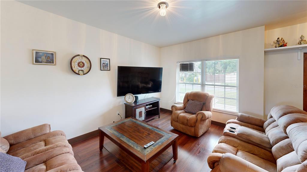 A living room features brown leather furniture, a television on a console, and wood flooring — 402 E MAPLE STREET, WINTER GARDEN, FL