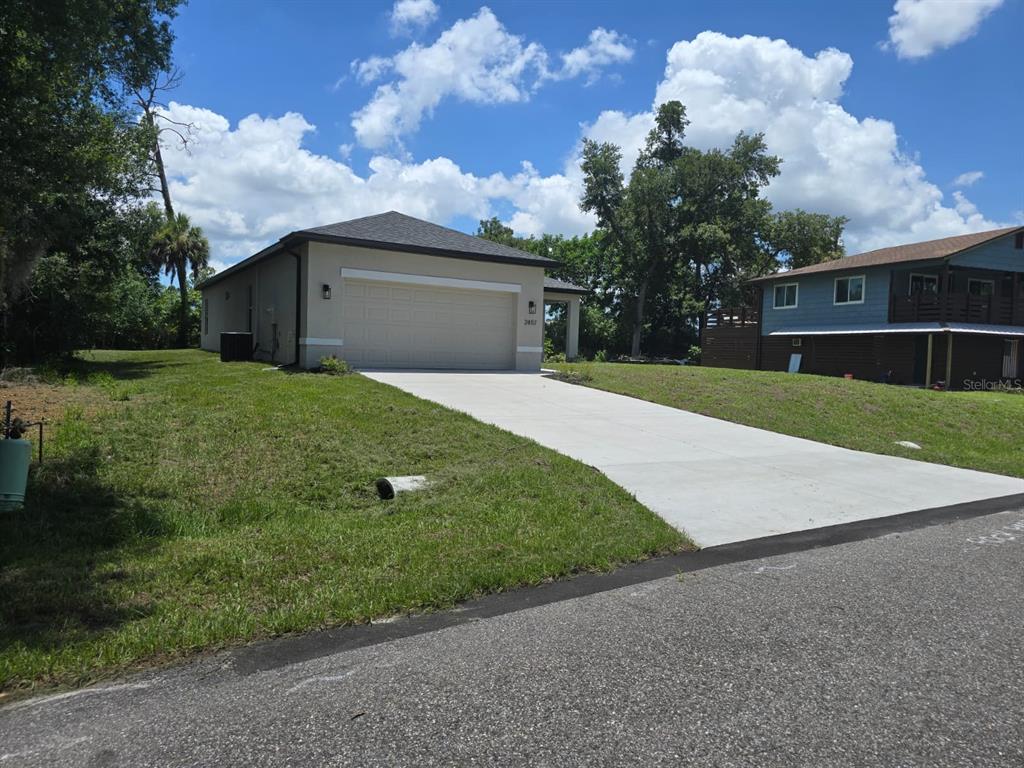A single-story house with a beige exterior, a two-car garage, and a concrete driveway — 2857 SHADY AVENUE, NORTH PORT, FL