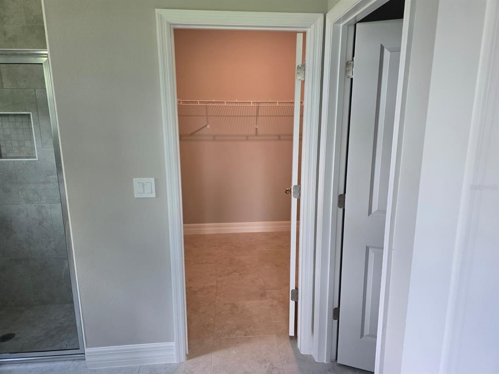 A walk-in closet with wire shelving is visible through an open doorway next to a shower — 2857 SHADY AVENUE, NORTH PORT, FL