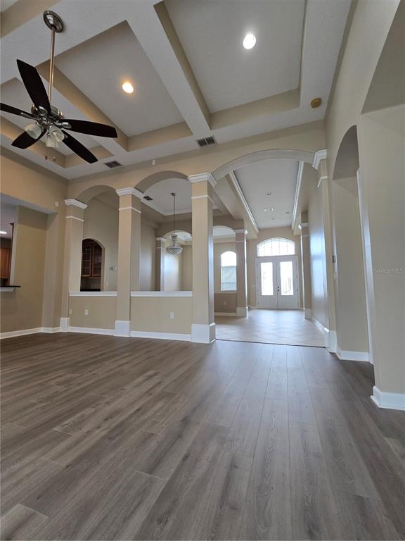 An open-concept living area features a coffered ceiling, arched columns, and wood-look flooring — 13613 LARSEN LANE, WINTER GARDEN, FL