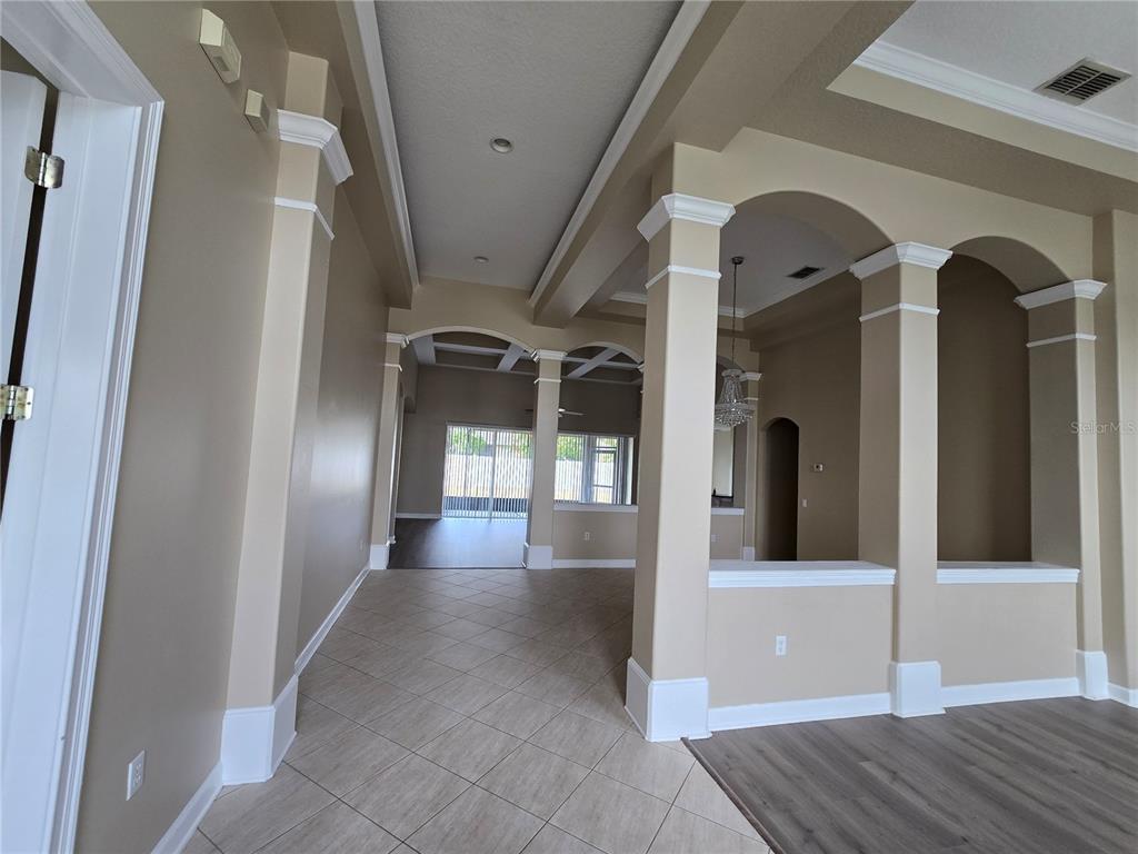 An interior view shows a tiled hallway leading to a living area with arched columns — 13613 LARSEN LANE, WINTER GARDEN, FL