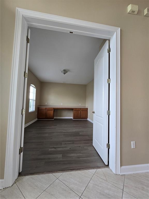 A room with wood-look flooring and a built-in desk is viewed through double doors — 13613 LARSEN LANE, WINTER GARDEN, FL