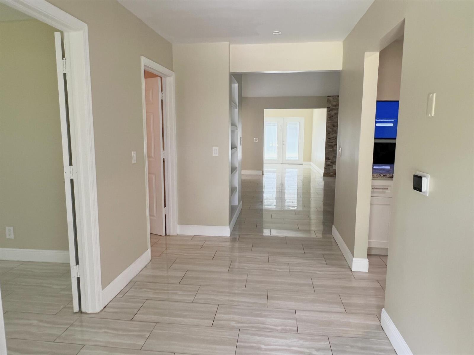 A hallway with light-colored tile flooring leads toward a room with glass double doors — 4811 N 122nd Dr Drive N, FL 33411, FL