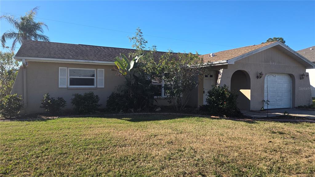 A single-story house with a tan stucco exterior, a garage, and a front lawn — 347 HOLLY ROAD, VENICE, FL