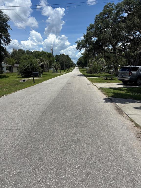 A paved residential street stretches into the distance under a blue sky with clouds — 2391 SE 176TH AVENUE, SILVER SPRINGS, FL