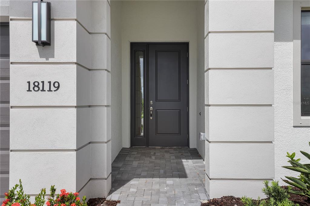 A dark front door with a side window is set within a white stucco entryway — 18119 CRESSWIND TERRACE, LAKEWOOD RANCH, FL