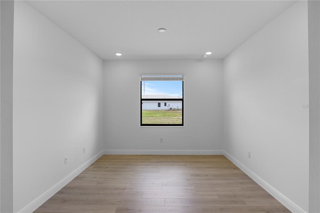 An empty room with light wood-look flooring, white walls, recessed lighting, and a single window — 18119 CRESSWIND TERRACE, LAKEWOOD RANCH, FL