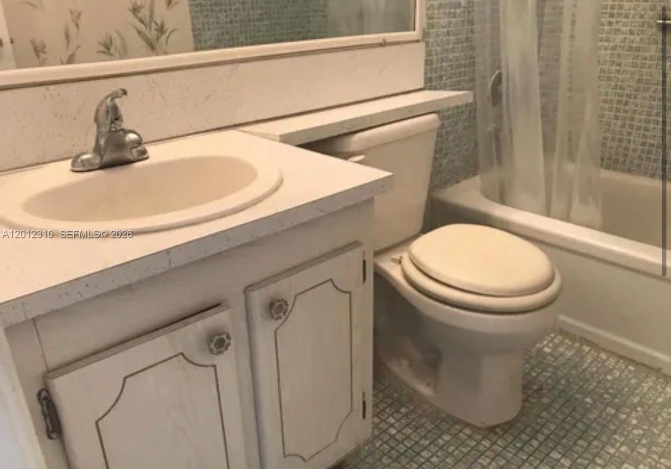 A bathroom features a white vanity with a sink, a toilet, and a tiled shower — WEST PALM BEACH, FL