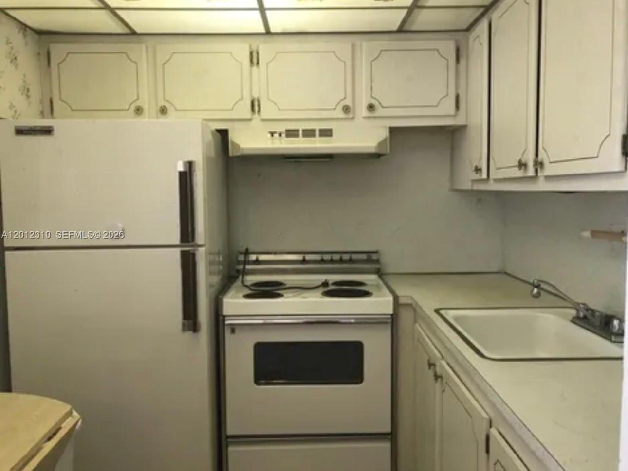A small kitchen features white appliances, white cabinets, and a drop-in sink — WEST PALM BEACH, FL