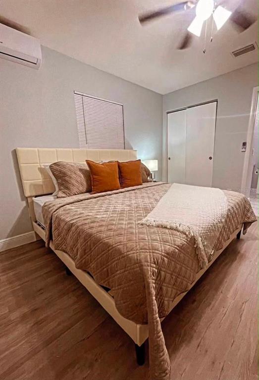 A bedroom features a beige upholstered headboard, a quilted bedspread, wood-look flooring, and a ceiling fan — 6504 N PACKWOOD AVENUE, TAMPA, FL