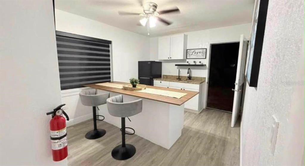 A kitchen features a wooden breakfast bar with two gray stools and white cabinetry — 6504 N PACKWOOD AVENUE, TAMPA, FL