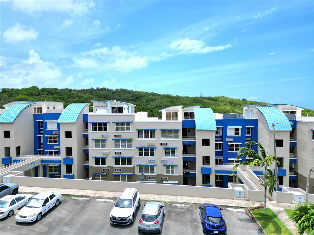 An exterior view of a multi-story apartment complex with blue roofs and a parking lot — 3 ST. MIRADOR PLAYA CONVENTO UNIT 10204, FAJARDO, PR