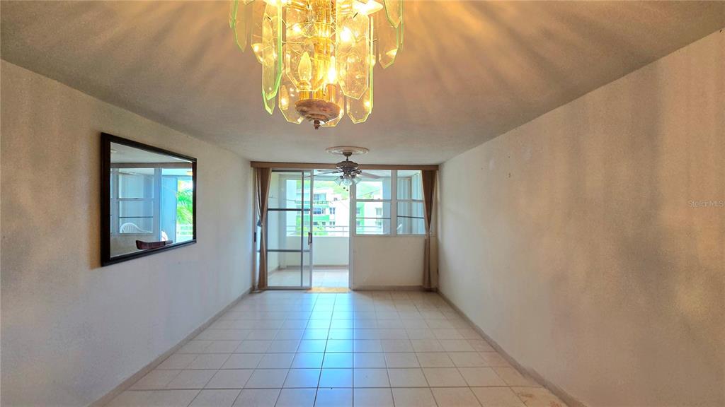 A dining room with tile floors, a crystal chandelier, and a sliding glass door balcony — 3 ST. MIRADOR PLAYA CONVENTO UNIT 10204, FAJARDO, PR