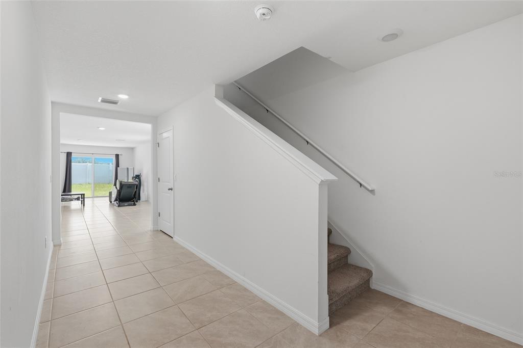 A hallway with tile flooring leads to a living area with stairs on the right — 24799 NW 11TH PLACE, NEWBERRY, FL