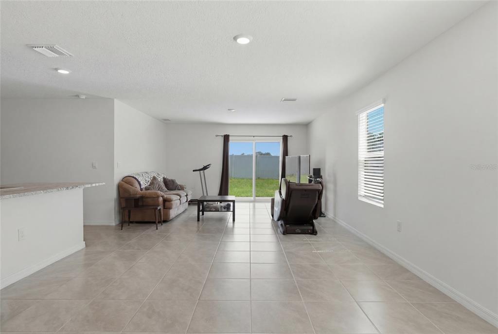 A living room with tile flooring, a brown sofa, a massage chair, and sliding glass doors — 24799 NW 11TH PLACE, NEWBERRY, FL