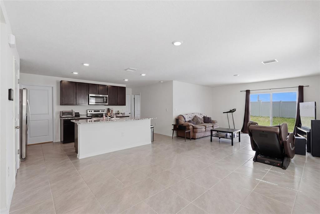An open-concept kitchen with dark cabinets and an island overlooks a living area with tile — 24799 NW 11TH PLACE, NEWBERRY, FL