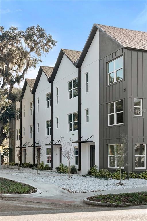 A row of modern three-story townhomes features white stucco walls, dark vertical siding, and gabled roofs — 1606 PARK LAKE STREET UNIT 9, ORLANDO, FL