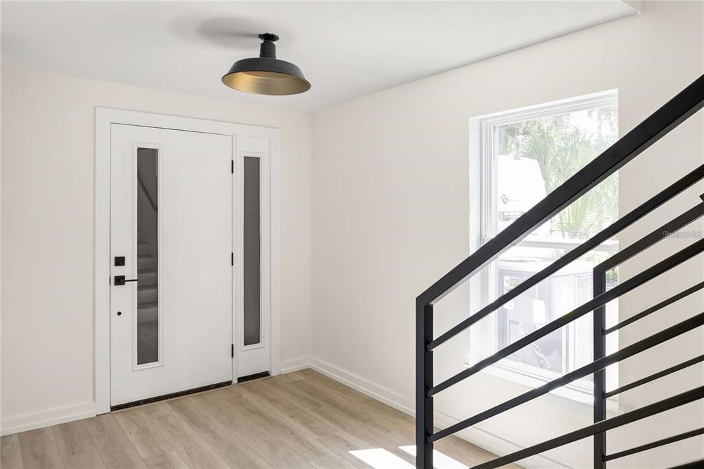 An entryway features a white front door with glass panels, light wood flooring, and stairs — 1606 PARK LAKE STREET UNIT 9, ORLANDO, FL