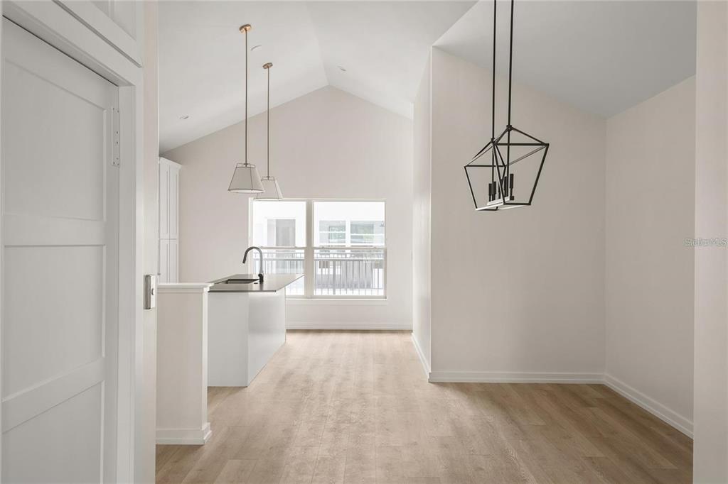 A bright kitchen and dining area features vaulted ceilings, light wood floors, and pendant lighting — 1606 PARK LAKE STREET UNIT 9, ORLANDO, FL