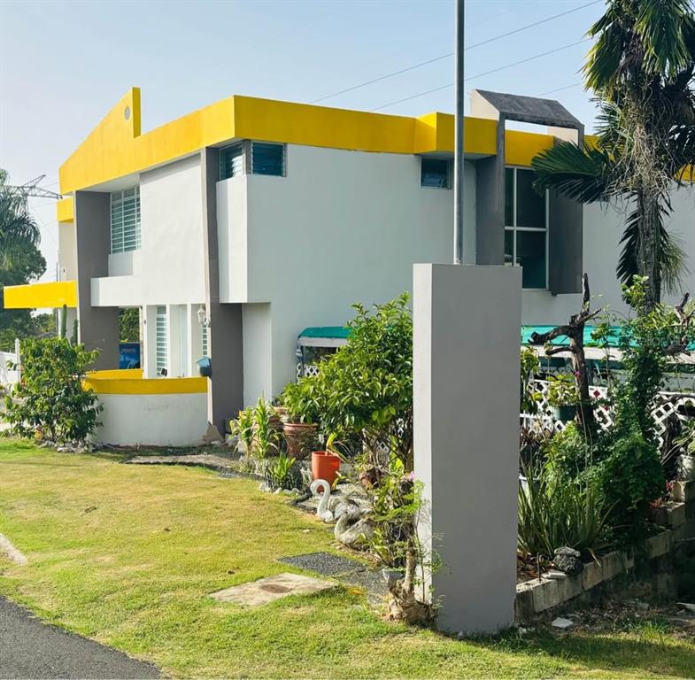A two-story house with white walls, yellow trim, and a prominent gray pillar in front — Bo. Dajao Cam Los Oyola BO. DAJAO, BAYAMON, PR