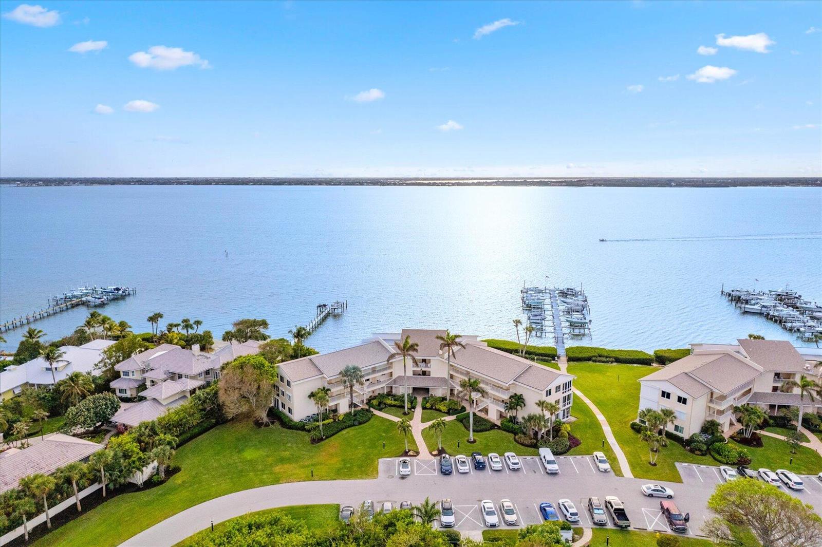 An aerial view shows waterfront apartment buildings with a parking lot and boat docks — 2370 NE Ocean Boulevard # A203, Stuart FL 34996, STUART, FL