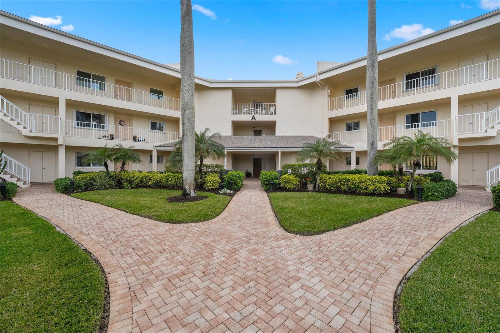 A three-story apartment building with a central courtyard, palm trees, and brick walkways — 2370 NE Ocean Boulevard # A203, Stuart FL 34996, STUART, FL