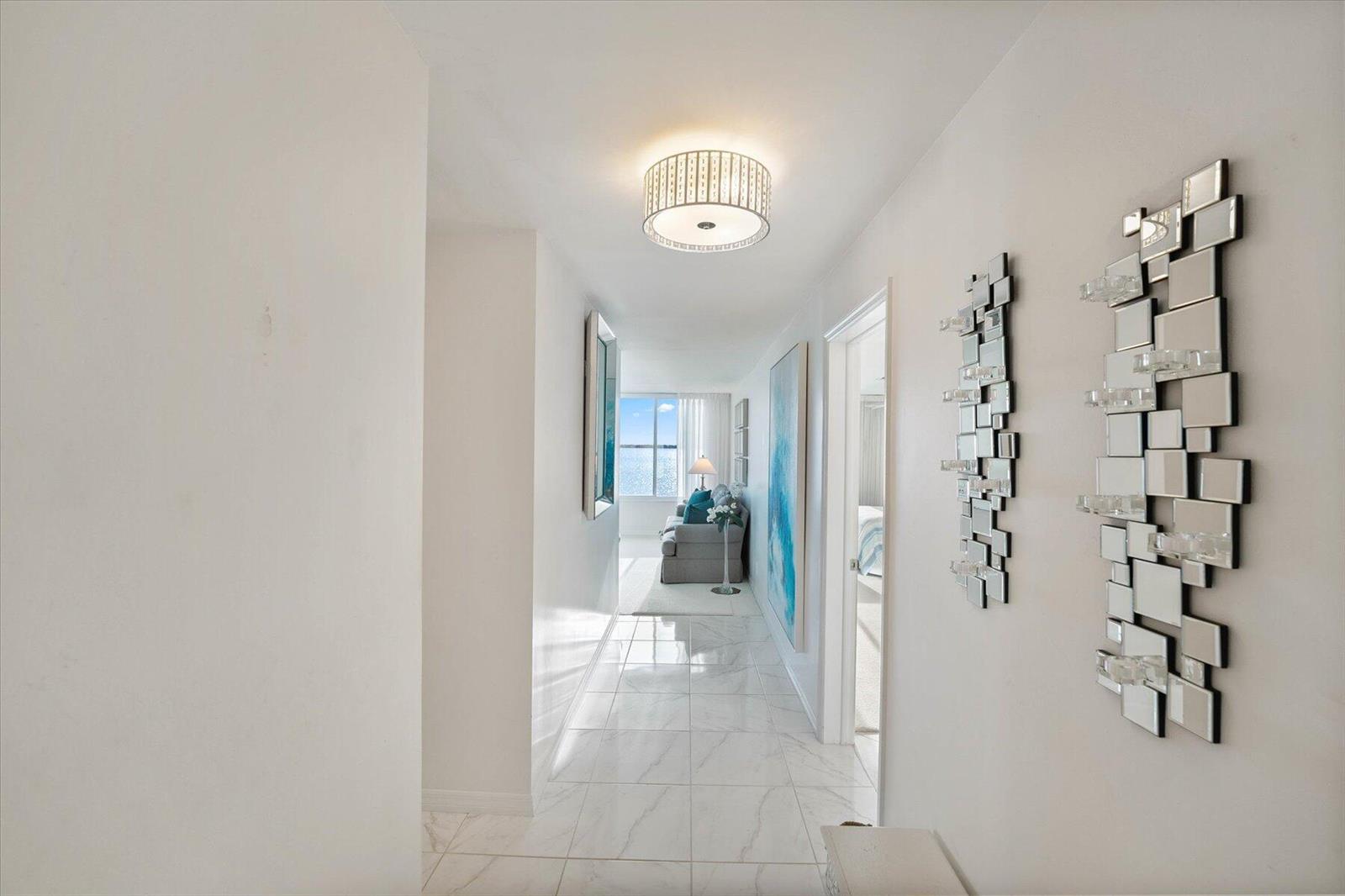 A bright hallway with white marble floors leads to a living area with ocean views — 2370 NE Ocean Boulevard # A203, Stuart FL 34996, STUART, FL