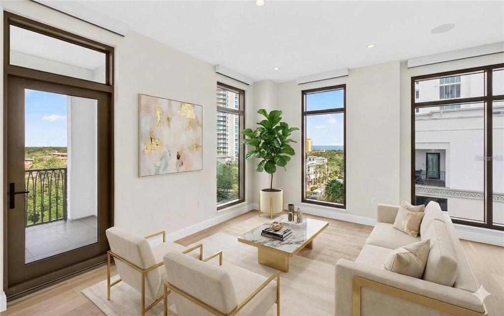 A bright living room features a sofa, two armchairs, a marble coffee table, and large windows — 126 4TH AVENUE NE UNIT 601, ST PETERSBURG, FL