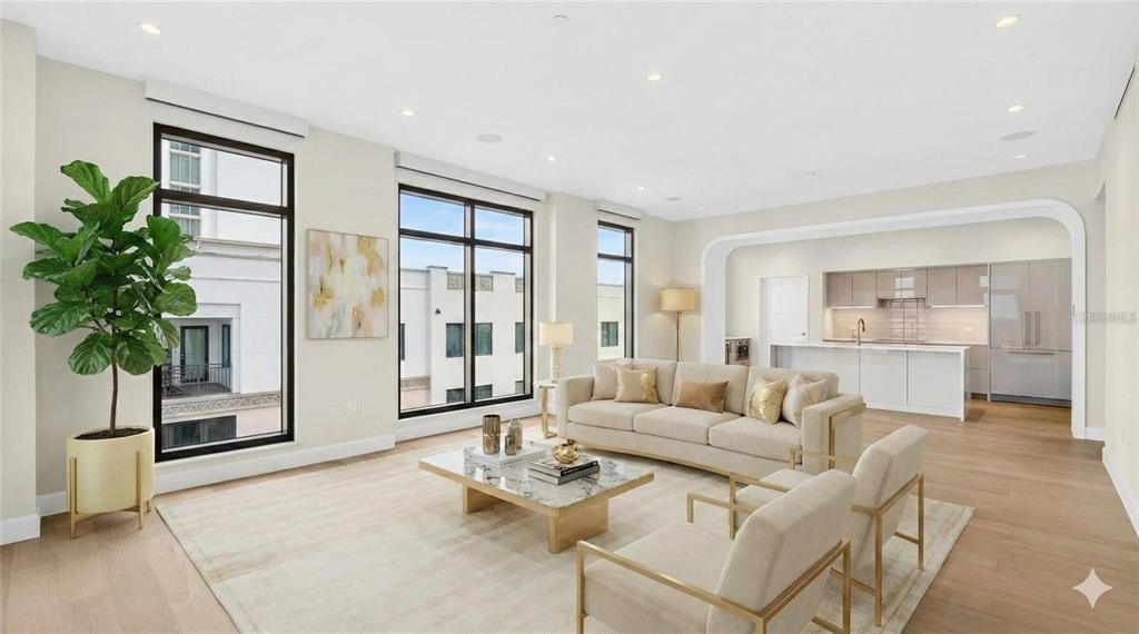A bright, modern living room with light wood floors, neutral furniture, and an open kitchen — 126 4TH AVENUE NE UNIT 601, ST PETERSBURG, FL