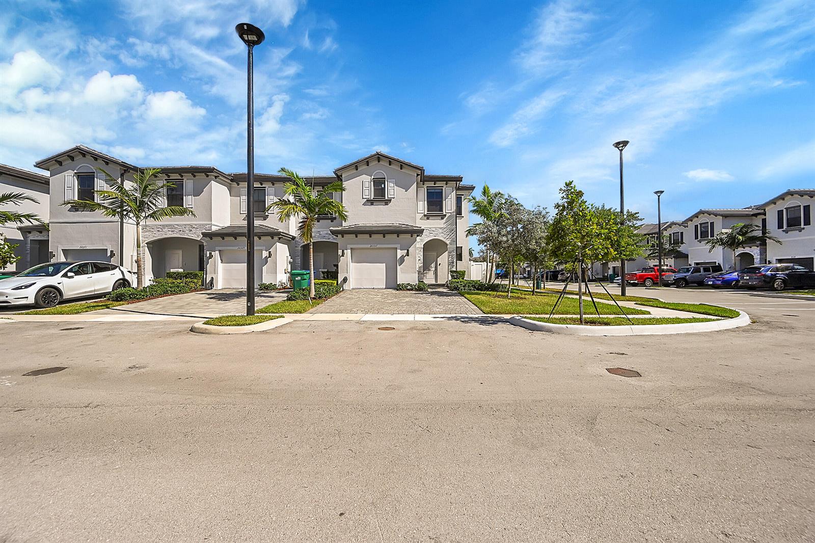 A row of two-story townhouses with attached garages and paved driveways under a blue sky — 20357 NW 4th Path, Miami Gardens FL 33169, MIAMI GARDENS, FL