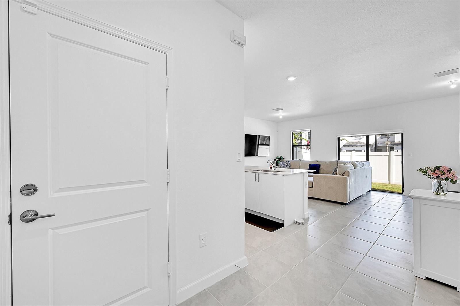 A white door opens into a bright, open-concept living area with tile floors and kitchen island — 20357 NW 4th Path, Miami Gardens FL 33169, MIAMI GARDENS, FL
