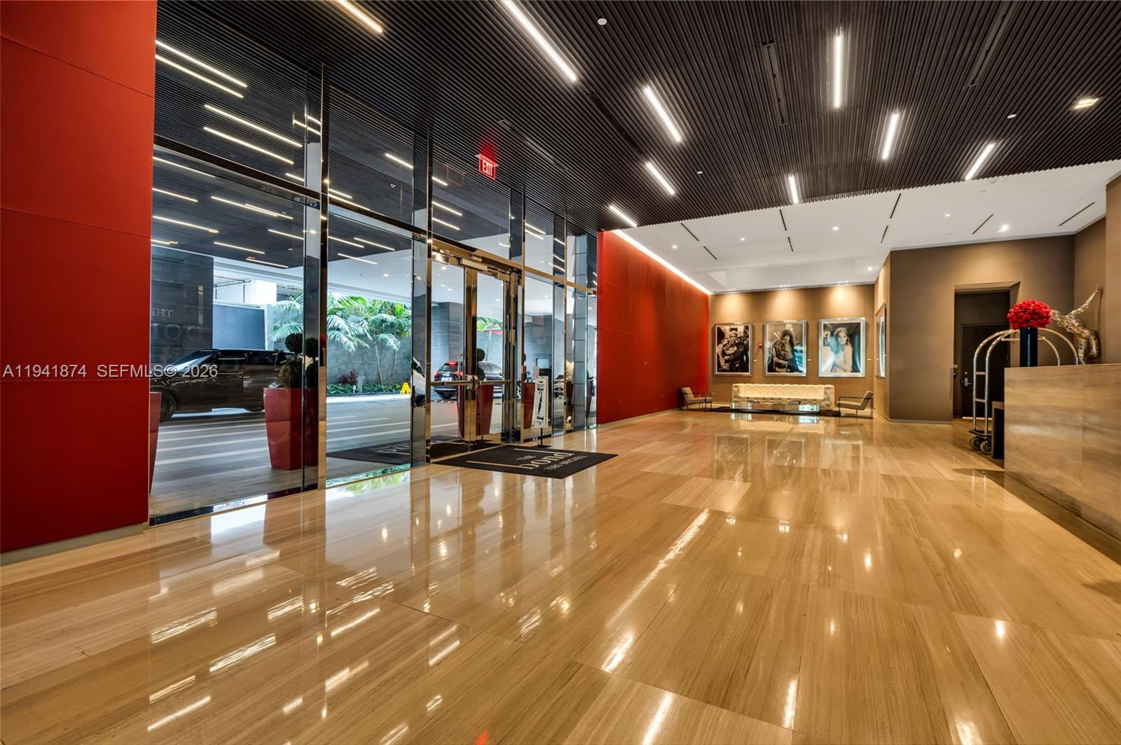 A modern building lobby features polished stone floors, red accent walls, and glass entry doors — 1080 Brickell Ave # 3901, Miami FL 33131, MIAMI, FL