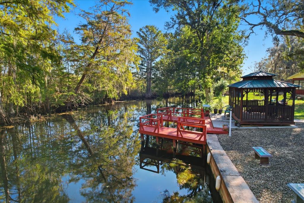 A red wooden dock extends into a calm canal next to a gazebo and trees — 11641 E SALMON DRIVE, FLORAL CITY, FL