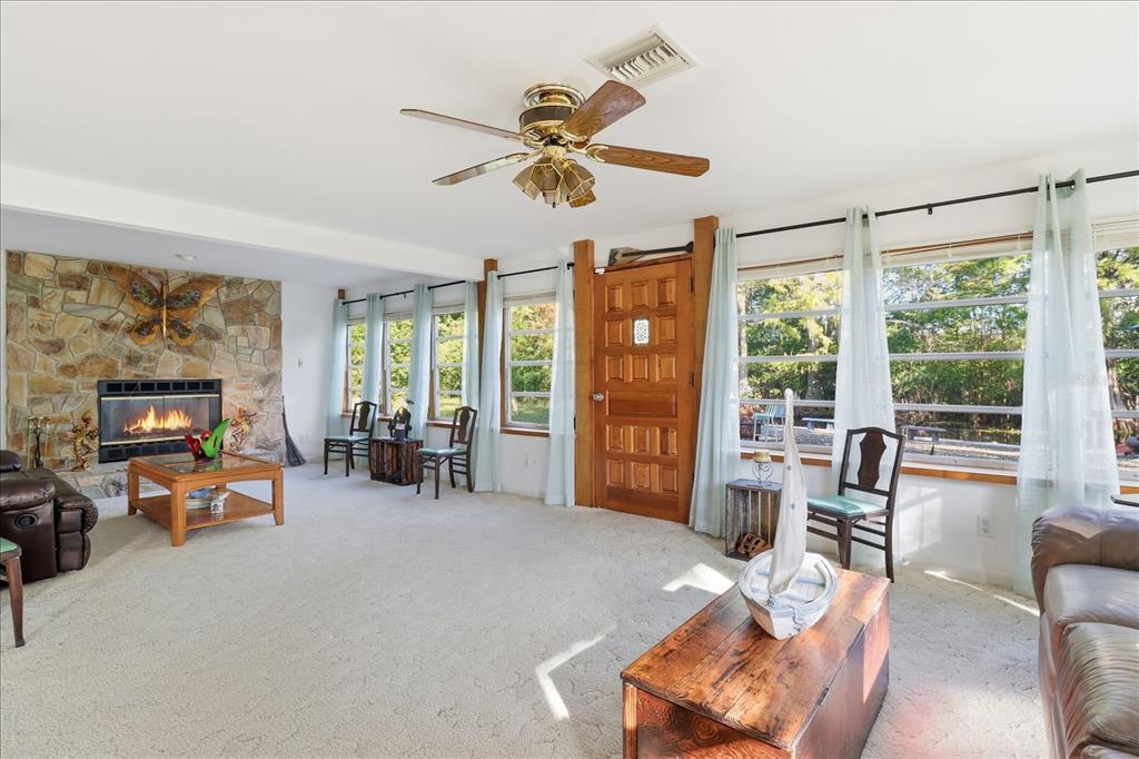 A living room features a stone fireplace, a wooden door, and large windows with curtains — 11641 E SALMON DRIVE, FLORAL CITY, FL