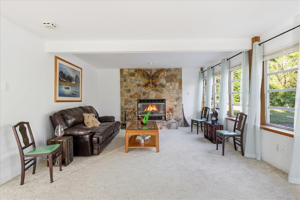 A living room features a stone fireplace, a brown leather sofa, and large windows — 11641 E SALMON DRIVE, FLORAL CITY, FL
