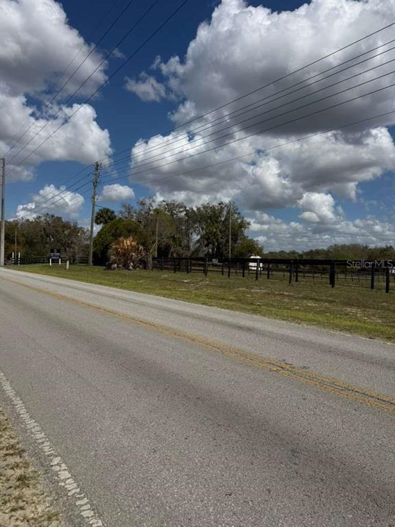 A paved road runs alongside a grassy field enclosed by a wooden fence — 0000 SW 140TH AVE, OCALA, FL