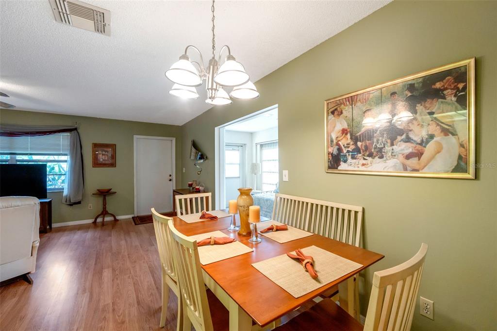 A dining room features a wooden table with chairs, a bench, and wall-mounted artwork — 1814 FOXHUNT DRIVE UNIT A, SUN CITY CENTER, FL